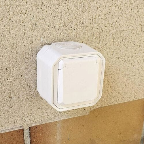 rénovation électrique d’une maison. Prise extérieure installée en façade d'un mur à Allan.