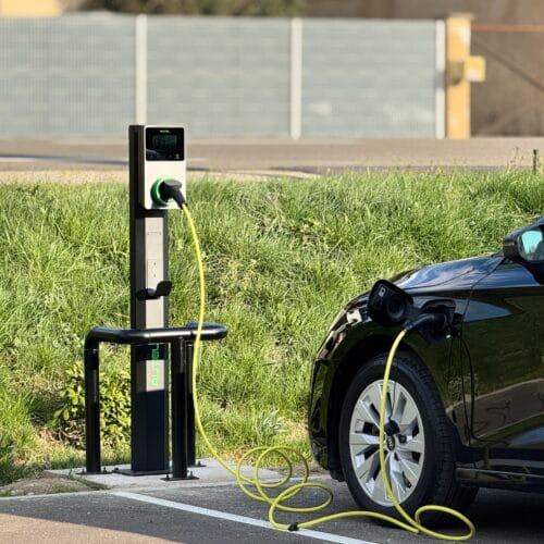 Borne de recharge électrique Autel MaxiCharger installée par QR ENERGIES chez Autoeasy Montélimar, connectée à un véhicule électrique en recharge, sur un parking extérieur avec pelouse et barrières métalliques.