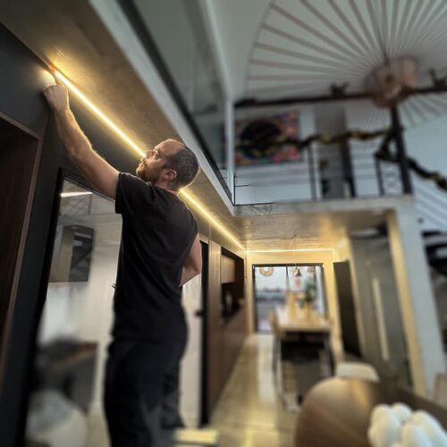 Antoine Ravix est en train d’installer un bandeau LED dans une maison.